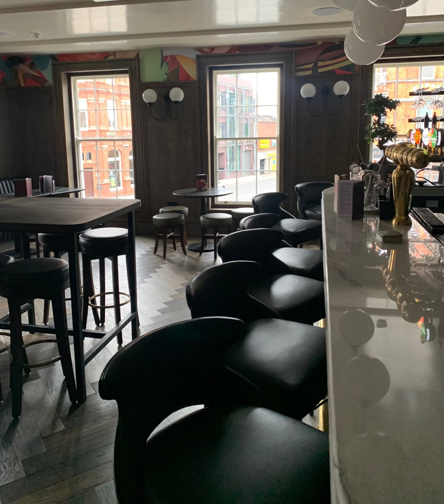 High tables by the windows, with leather bar stools along a marble counter.