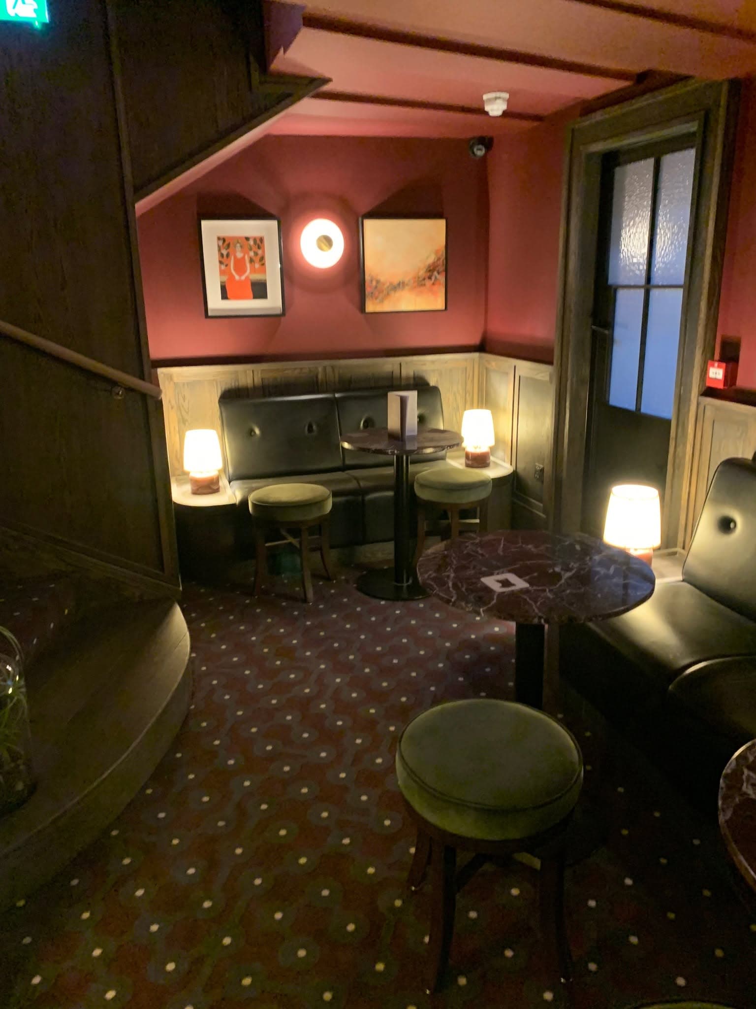 A quieter snug with banquette seating, wall lights and a patterned carpet.